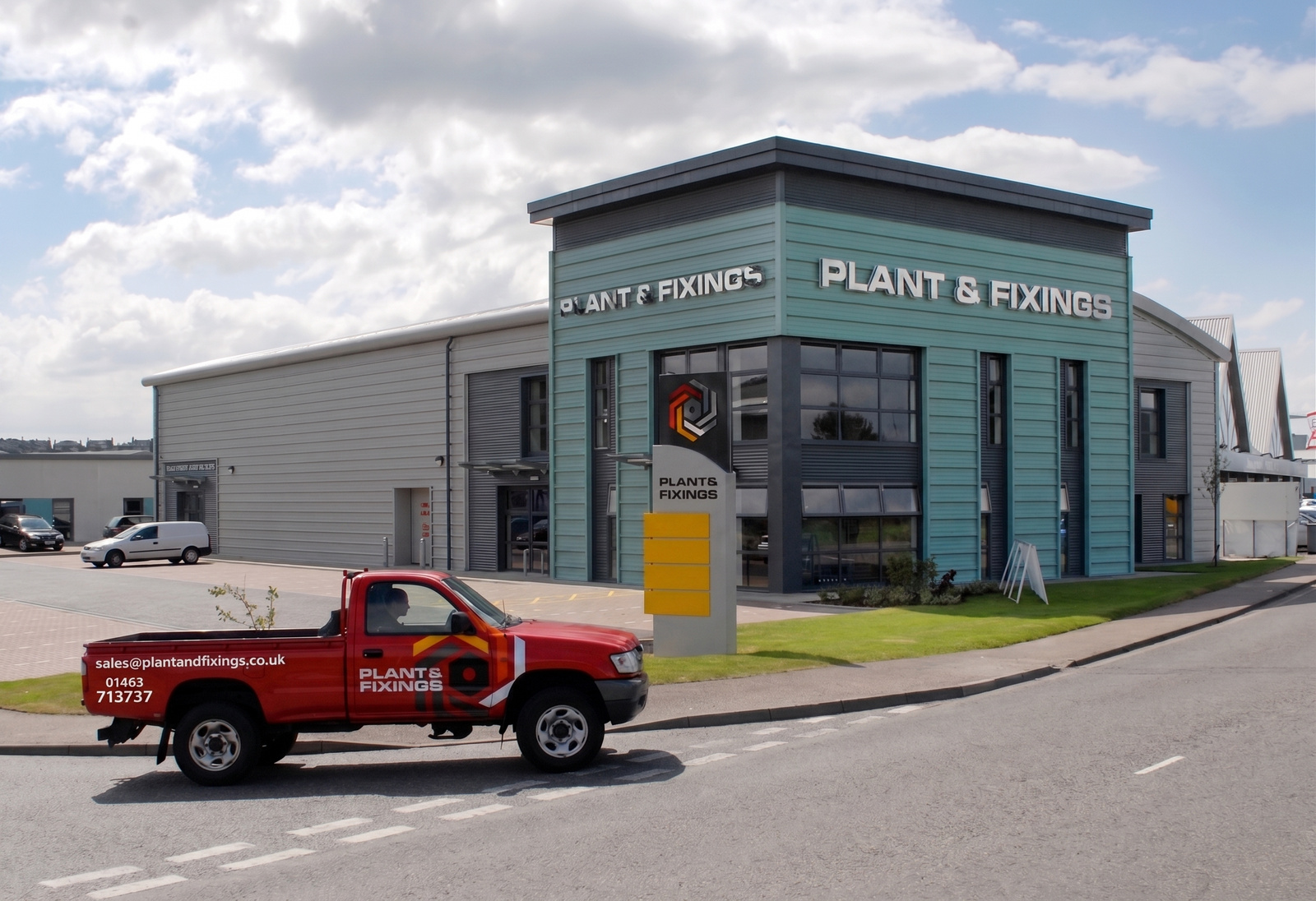 The Plant and Fixings premises on Harbour Road, Inverness, with a liveried pickup passing on the road outside